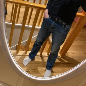 Blå jeans från Replay - Snygga blå jeans från Replay med klassisk femficksdesign och knappgylf. Perfekta för en avslappnad stil. Märkeslappen i läder baktill ger en extra touch. Storleken är 28 midja och 32 längd. Skicket är 8/10🤙 det finns ett litet ihopsytt hål i fickan, vilket är den ända defekten.