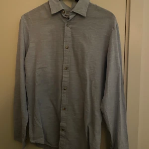 Ljusblå linneskjorta - Snygg ljusblå skjorta från jack and Jones med klassisk krage och knäppning framtill. Skjortan har långa ärmar med manschett och är tillverkad i linne. Perfekt för en clean och stilren look.