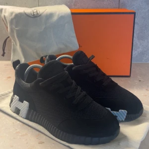 Svarta sneakers  - Svarta sneakers med chunky sula och stort H i silver på sidan. Ovandelen är i mesh och mocka med snygga detaljer och snörning. Snygg, modern design som sticker ut med den räfflade sulan och exklusiv känsla. Perfekt för dig som gillar lyxiga streetwear-vibbar.