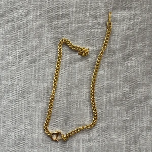 Guldfärgat halsband med C-detalj - Snyggt guldfärgat halsband med kedja i klassisk design och en C-formad detalj framtill. Perfekt accessoar för att lyfta din outfit med en touch av lyxig känsla. Passar dig som gillar statement-smycken och stilrena detaljer.