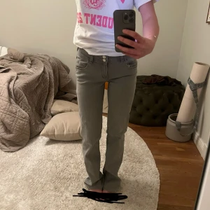 Grå bootcut jeans med dubbla knappar - Säljer ett par grå jeans med bootcut passform och dubbla knappar och lågmidja. Något slitna nedtill men inget som märks. Strl 164 men passar mig som normalt har 34