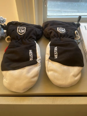 Svarta och vita Hestra vantar - Här har du ett par riktigt schyssta hestra vantar som kostar 599kr ny pris ligger på runt 1200-1500kr det är storlek 7 junior storlek vantarna håller dig riktigt varmt om händerna i skidbacken eller bara ute i naturen märket är väldigt stort och fint märke har inga skador är använda ett fåtal med gånger. Till dig som vill ha något lite extra eller bra i skidbacken eller i naturen så kommer de här att vara perfekta till dig så passa på nu när det är så bra pris!!! Fraktar 🚚📦snabbt 👍