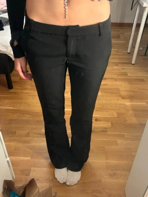 Svarta kostymbyxor tall från Bik Bok - Snygga svarta kostymbyxor från Bik Bok i storlek 36. Byxorna har en klassisk rak passform med midwaist och bälteshällor. Materialet är mjukt och har en lätt stretch för extra komfort. Perfekta för en clean och stilren look.