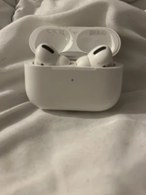 AirPods Pro - Apple AirPods Pro med laddningsetui. Trådlösa hörlurar med aktiv brusreducering och transparensläge. Skick: synligt yttre slitage på etuiet, men hörlurarna fungerar och laddar som de ska. Perfekt för musik, samtal och träning.