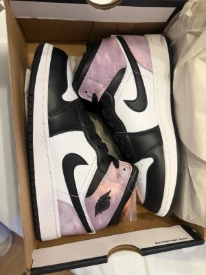 Nike Air Jordan 1 Mid Bleached Coral LIMITED EDITION STRL 38,5 - Säljer ett par Nike Air Jordan 1 Mid SE i färgen Black/Bleached Coral-White. Skorna har svart och vit skinnpanel, med rosa/lila blekta detaljer i textil och klassisk svart swoosh. Kommer med extra korallfärgade skosnören. Perfekt för dig som vill sticka ut.