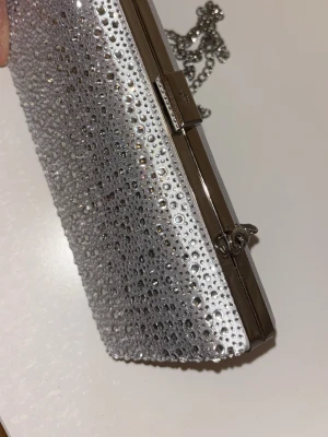 Kuvertväska - Snygg väska som går att ha till fest outfits och balklänningar. Aldrig använd så inga defekter alls. Silvrig och skönt material. Kedja ingår fråga efter längd o annat om det behövs💞🌸