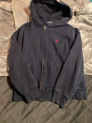 Polo Ralph lauren hoodie - Mörkblå polo Ralph lauren hoodie i färgen mörk blåe skicket är väldigt bra och passar folk som är runt 149/ 10-12 år