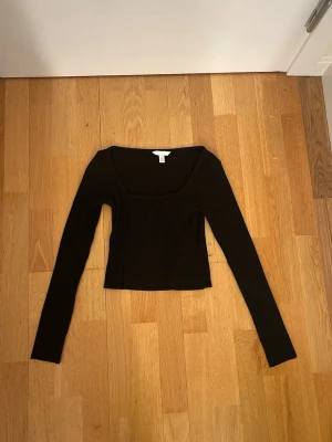 Svart ribbad långärmad topp H&M XS - Svart ribbad långärmad topp från H&M i storlek XS. Toppen har en fyrkantig urringning. Perfekt att styla med jeans eller kjol för en clean look.