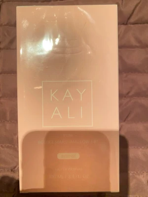 Kayali Yum Boujee Marshmallow - Intensiv Eau de Parfum med noter av freesia, jordgubb, rosa marshmallow, krämig kokos, vispad vanilj och rosa mysk. Volym: 100 ml. Ingredienser inkluderar alkohol, parfym, vatten, etylhexyl metoxycinnamat, limonen, linalool m.m. Tillverkad i Frankrike.