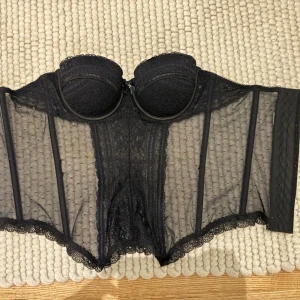 Svart korsett  - Svart korsett. Stretchig och har många hylsor så passar nog flera storlekar. Lapp bortklippt men är i storlek 75B.