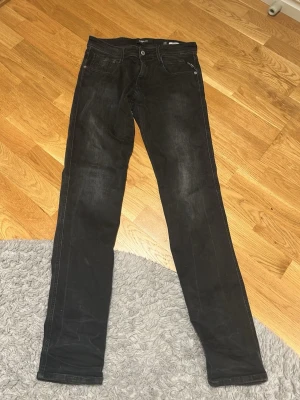 Replay svarta jeansbyxor 30/34 - Svarta jeansbyxor från Replay i modellen Anbass. Snygg, smal passform med klassisk femficksdesign och knappgylf. Materialet är slitstarkt jeans och färgen är mörk svart med lätt tvättad look. Perfekt för dig som gillar stilrena och moderna jeans. Använda max 3 gånger då jag tröttnade på tightare jeans. Vill rensa garderoben och få in pengar. 