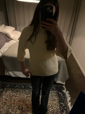 Ljusbeige polotröja med ribbade detaljer - Säljer en ljusbeige polotröja med bred ribbad krage, muddar och nederkant. Tröjan är stickad och har trekvartsärmar, perfekt för dig som gillar enkel och clean stil. Materialet är mjukt och känns skönt mot huden. Tröjan är i så gott som nytt skick då jag använt den 1-2 gånger, passar den som var storlek xs eller s.