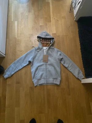 Burberry zip hoodie - En fin burberry zip hoodie i storlek S men är väldigt liten i storleken så den passar förmodligen XS bättre. Hoodien är i nyskick och är aldrig använd. Hör av er vid frågor och funderingar!