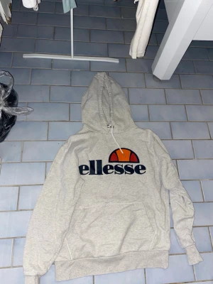 En Hoodie från Ellesse - Jag säljer en hoodie från ellesse som är en vit hoodie med ellesse märket på den med loggan också hoodien har storleken Loch passar för både kvinnor och män och passar för en massa stilar 