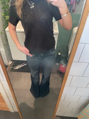 Mörkblå bootcut jeans med slitningar från cheap Monday  - Säljer ett par mörkblå bootcut jeans med snygga slitningar och tvättade detaljer. Jeansen har låg midja och klassisk femficksmodell. Materialet är jeans med lite stretch för skön passform. Perfekta till sneakers eller boots!