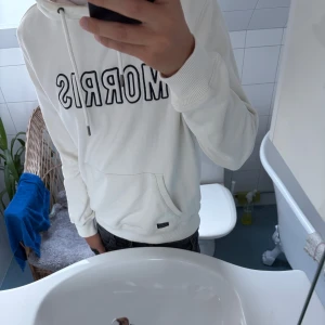 Vit Morris Hoodie - Tja! Säljer en tvär fet Morris Hoodie. 10/10 skick förutom en liten skada vid snöret. Hör av dig om du har någon fundering!