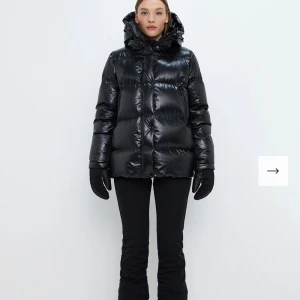 Svart pufferjacka från 8848 Altitude - Säljer en svart, glansig pufferjacka från 8848 Altitude med stor huva och dragkedja framtill. Jackan har quiltad design, sidofickor med dragkedja och en patch med logga på ärmen. Perfekt för dig som vill ha en varm och snygg vinterlook. Jackan är endast använd en vinter, inga defekter, nypris 5500 kr. Skriv för egna bilder!!