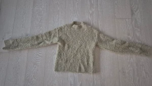 Beige fluffig stickad tröja Monki XS - Supermysig beige stickad tröja från Monki i storlek XS. Tröjan har lång ärm och en lite högre rund hals. Materialet är fluffigt och ger en cool textur, perfekt för att hålla dig varm och snygg under kyliga dagar. Enkel att matcha med jeans eller kjol.
