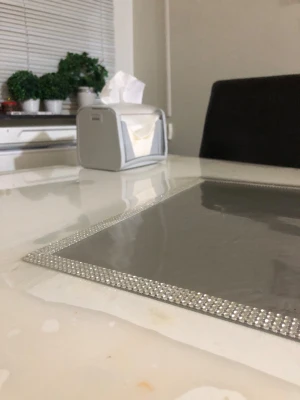 Papper - Ingen elektronikprodukt synlig på bilden. Bilden visar ett bord med en servetthållare och dekorativa växter i bakgrunden, men ingen elektronik som kan beskrivas eller kategoriseras enligt taxonomierna.