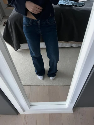 Mörkblå raka jeans med slitna benslut - Mörkblå jeans med rak passform och klassisk femficksdesign. Jeansen har slitna och fransiga benslut för en avslappnad vibe. Tillverkade i jeansmaterial och har normal midja. Perfekta för dig som gillar en lite mer chill och vintage look.