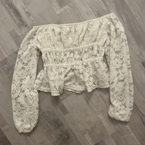 Vit spets blus offshoulder H&M - Passar som S för mig som är 160! Superfin vit blus från H&M med offshoulder och långa ärmar. Blusen är gjord i spets med blommigt mönster och har volangdetaljer vid midjan och nederkant. Elastisk upptill och vid ärmslut.