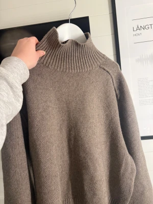 Beige stickad polotröja - Säljer en beige stickad polotröja med ribbad hög krage och långa ärmar. Tröjan har en enkel och clean look med ribbade muddar vid ärmslut och nederkant. Perfekt för dig som gillar neutrala färger och vill ha en mysig tröja till garderoben.