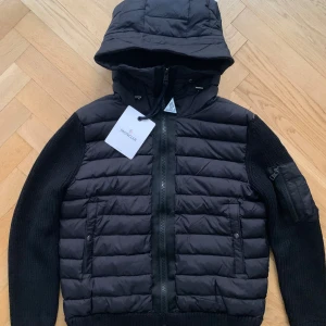 Svart Moncler cardigan med huva - Svart cardigan från Moncler med stickade ärmar och vadderad kropp. M men sitter som S. Otroligt bra kvalité. Bättre hittar du inte, därav priset.