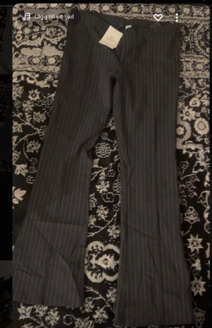 Randiga kostymbyxor från H&M Divided - Snygga svarta kostymbyxor med tunna vita ränder från H&M Divided. Byxorna har raka ben och klassisk passform, perfekta för en stilren look. Materialet är mjukt och bekvämt, och midjan är normal. Passar dig som gillar en clean och trendig vibe.Helt nytt.(priset går att diskuteras vid snabb köp)