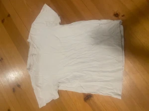 Vit t-shirt från lager 157, storlek S - En klassisk vit t-shirt från 157 i storlek S. T-shirten är helt enfärgad, har korta ärmar och är tillverkad i mjuk 100% bomull. Perfekt för dig som gillar enkel och clean stil. Passformen är normal och halsen är rund.