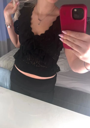 Svart spetsig blus från Zara - Supersöt svart topp i storlek S  från Zara med volanger och spetsdetaljer. Lite svårt att se på bilden med den går ungefär till naveln. Nästintill oanvänd.