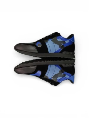 Valentino Rockrunner blå sneakers - Säljer ett par Valentino Rockrunner sneakers med blått och svart camouflage-mönster. Skorna har snörning, platt sula och rund tå. Materialmix av skinn och syntet med coola detaljer på hälen. Kommer med originalkartong i matchande camo-design.
