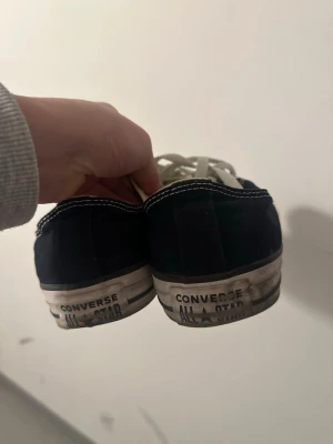 Svarta Converse All Star sneakers - Klassiska Converse All Star sneakers i svart canvas med vita snören och tåhätta. Skorna har vit sula med svart rand och tydlig logga på hälen. Låg modell med rund tå och kontrastsömmar. Perfekta för en avslappnad och cool stil.