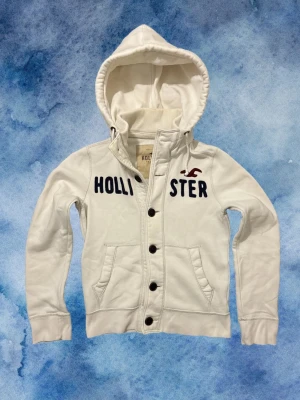 Vintage Hollister Cardigan Med Knappar - Säljer denna as feta Hollister Cardigan Med Knappar, sjukt sällsynt och eftertraktad | Mycket bra skick | Storlek S | Längd ≈61cm, Bredd armhåla-armhåla ≈50cm | Model 175cm, 68kg | Pris kan diskuteras 