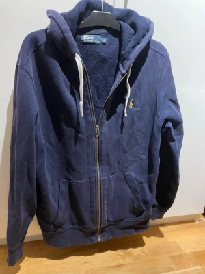 Blå Ralph lauren hoodie  - Säljer nu denna snygga Ralph lauren hoodie med gul logga och storleken XL. Används sparsamt.