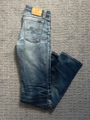 Blå jeans från Nudie Jeans - Jätte snygga jeans från nudie Längd:108cm Midja 38cm tvärs över benöppning:18cm tvärs över model oklar då lappen har suddats ut