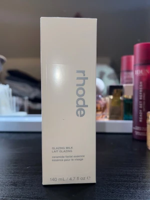 Rhode Glazing Milk Essence 140 ml - Helt ny. Har 2 st så säljer ena.                           Rhode Glazing Milk är en ceramidbaserad facial essence i en stilren, ljusgrå plastflaska på 140 ml. Produkten ger huden en återfuktad och fräsch känsla och har en mjölkig konsistens. Perfekt för dig som vill ha glow och extra återfuktning i din hudvårdsrutin.