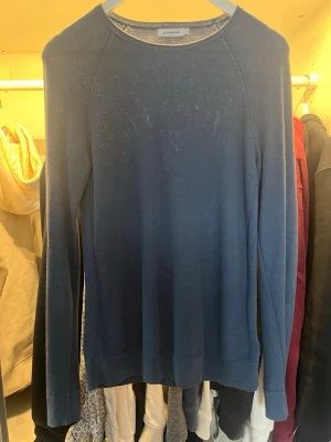 Blå stickad tröja från J.Lindeberg - Snygg blå stickad tröja från J.Lindeberg med rund hals och långa ärmar. Enkel och stilren design. Mjuk och skön kvalitet i ett klassiskt snitt. Bara att komma privat om frågor eller mer bilder.