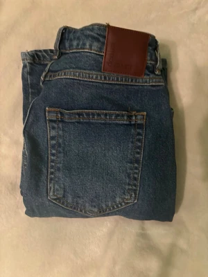 Blå wide graze jeans - Säljer ett par blåa wide jeans från bikbok med raka ben. Klassisk femficksmodell med snygga sömmar och knappstängning. Jeansen är i ett mjukt denimtyg och har en cool vintage vibe. Perfekta till sneakers eller boots.