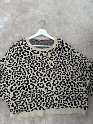 Leopardmönstrad stickad tröja Gina Tricot - Säljer en beige och svart stickad tröja från Gina Tricot i storlek L. Tröjan har ett coolt leopardmönster, rund halsringning och långärmade, loose passform. Storlek L men passar mig med S/M