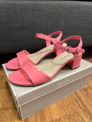 Rosa sandaler med klack från Tamaris - Ett par aldrig använda klackar i storlek 39 ifrån Tamaris! Super fint skick💕 fråga gärna om fler bilder/ mått och buda gärna❤️ Skorna är i originalförpackning men har inte prislappen kvar! 