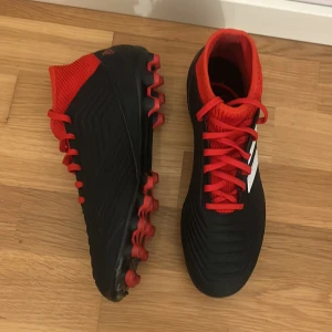 Adidas Predator fotbollsskor - Säljer ett par oanvända Adidas Predator 18.3 fotbollsskor. Skorna har snörning, platt sula med dobbar och en stickad, högre krage för extra stöd. (utesko) pris kan diskuteras!