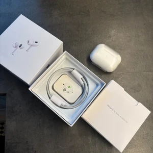 AirPods Pro (2nd generation) - Apple AirPods Pro (2nd gen) med originalförpackning och tillbehör. Trådlösa hörlurar med aktiv brusreducering, laddningsetui och USB-C kabel. Produkten ser ut att vara i mycket gott skick utan synligt slitage. Perfekt för musik, samtal och träning.