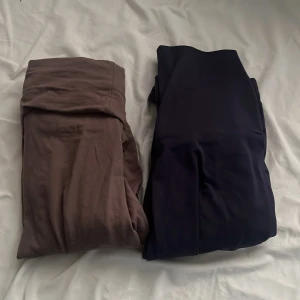 Två par leggings i brunt och mörkblått - Säljer två par mjuka yoga pants/ leggings, ett par i brun och ett par i mörkblå färg. Båda är stretchiga och har en hög midja, perfekta för en chill och bekväm stil. Materialet känns lent och följsamt mot huden.