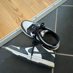 Nike Dunk Low svart/vit sneakers - Säljer ett par Nike Dunk Low sneakers i svart och vitt skinn med klassisk swoosh på sidorna. Endast Använd på en resa 