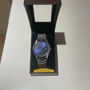 Sekonda klocka med blå urtavla - Stilren klocka från Sekonda med metallarmband i silver och en rund blå urtavla. Klockan har datumvisning och klassisk länkdesign. Perfekt accessoar för dig som gillar en clean och modern look.