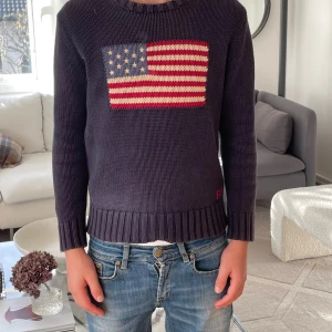 Mörkblå stickad tröja Polo Ralph Lauren - ‼️Mycket eftertraktad stickad tröja från Polo Ralph Lauren‼️ 🇺🇸🇺🇸Tröjan har ett broderi av den amerikanska flaggan framtill och RL-broderi🇺🇸🇺🇸 nertill. Tröjan har rund halsringning, ribbade muddar och lång ärm. Perfekt för dig som gillar en avslappnad och elegant stil. Sitter lite litet på mig som är 163 så passar nog bäst om du är mellan 155 - 160.  Vid frågor och funderingar är det bara att slå en pling❗️