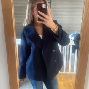 Kappa - Säljer en klassisk mörkblå skepparkavaj med dubbelknäppning och bred krage. Jackan har en rak passform och är tillverkad i ull, perfekt för kyligare dagar. Snygg och tidlös modell som passar till jeans eller dressat.