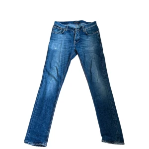 Blå Nudie Jeans - Tja! Säljer dessa feta marinblå jeans från Nudie jeans med snygga urtvättningar och små slitningar. I fint men använt skick (litet hål i höger ficka, se bild 5), i modellen Grim Tim (Slimfit). Skriv vid minsta fundering, priset är självklart inte ristat i sten🤩🤩🤩