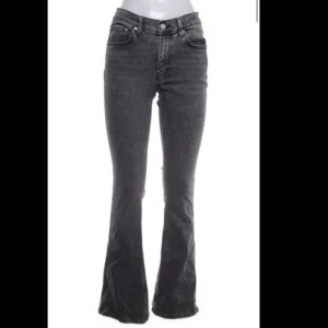 Grå bootcut jeans från Gina Tricot - Snygga grå jeans från Gina Tricot med bootcut-modell och midwaist. Jeansen har klassisk femficksdesign, dragkedja och knapp framtill samt bälteshällor. Perfekta för dig som gillar en trendig och bekväm look.