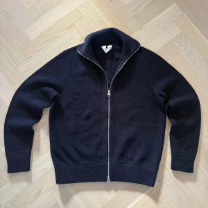Klassisk zip-tröja från ARKET – Mörkblå - Stilren och tidlös stickad tröja från ARKET i mörk marinblå färg. Modellen har dubbel dragkedja, hög krage och är perfekt till vardag! Kvalitén är mjuk och hållbar i en blandning av bomull och ull.  Detaljer:     •    Märke: ARKET     •    Storlek:M/L     •    Färg: Mörkblå / Navy     •    Material: Bomull & ull     •    Modell: Stickad zip-tröja     •    Passform: Normal     •    Skick:Mycket sparsamt använd  Nypris:1100  Övrigt: Inga fläckar eller hål. Fräsch och välvårdad. Passar utmärkt året